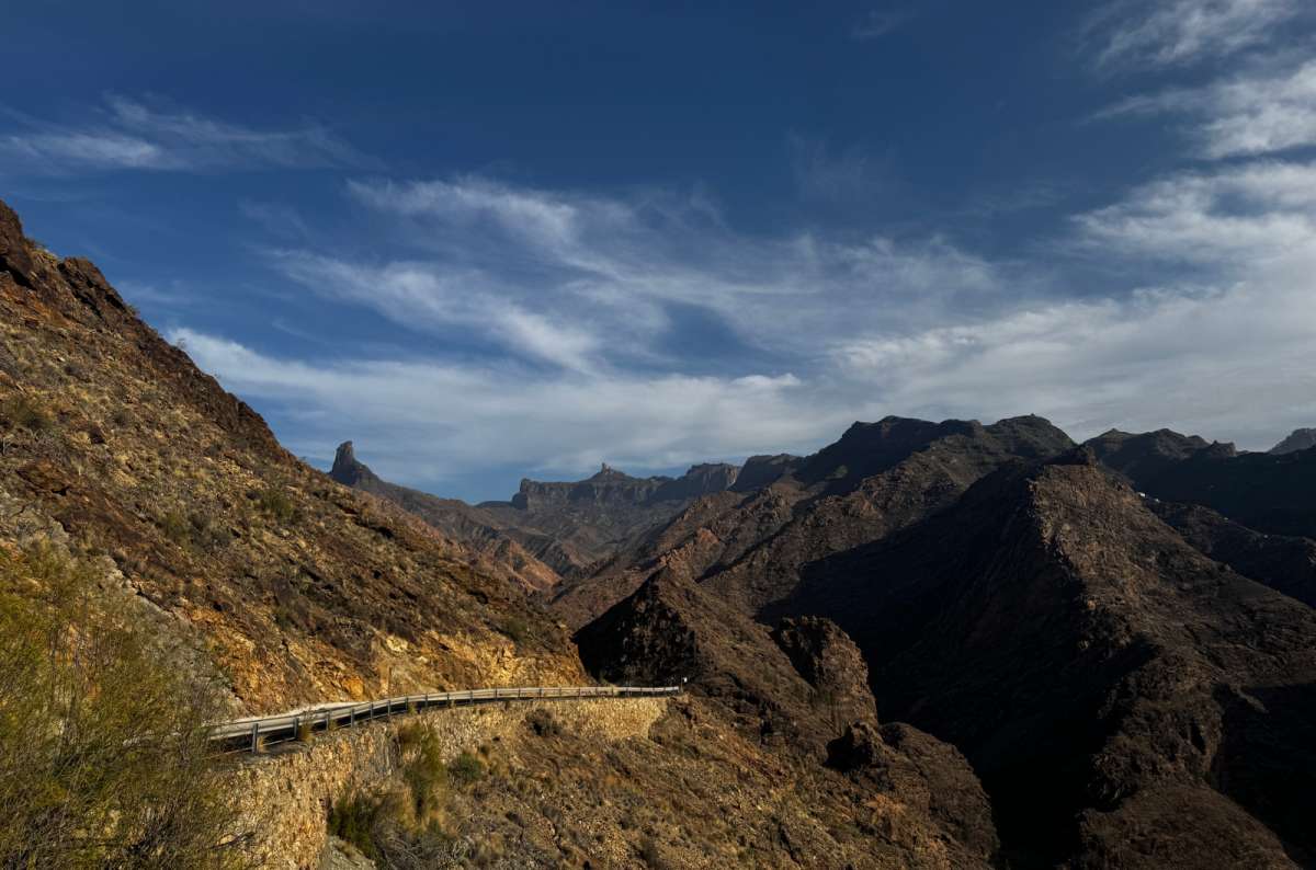 a photo of the GC-210 mountain road curving along a steep ridge with jagged peaks in the distance, Canary Islands, photo by Next Level of Travel