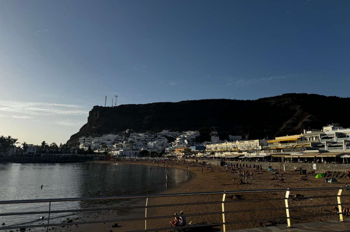photo of the whitewashed town of Puerto de Mogán with its beach and a steep headland behind at dusk, Canary Islands, photo by Next Level of Travel