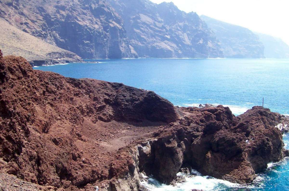 a photo of dramatic volcanic coastal cliffs and rugged rock formations meeting the ocean, Teno, Tenerife