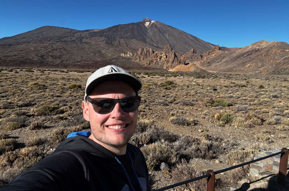 a photo of a tourist smiling with Mount Teide and the Roques de García rock formations behind, Teide National Park, Tenerife, photo by Next Level of Travel