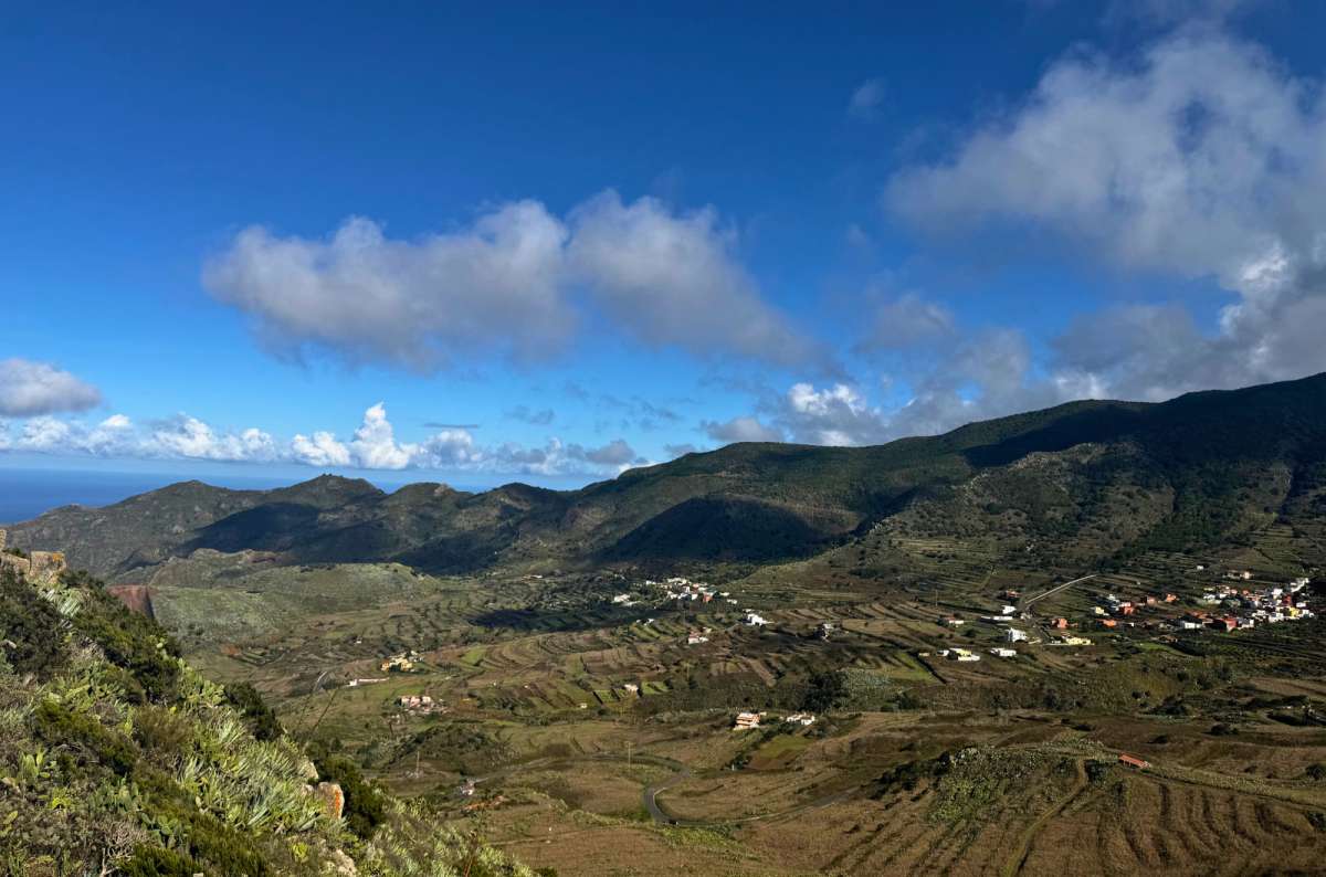 a photo of terraced farmland and a village in a valley surrounded by the Teno mountains, Tenerife, photo by Next Level of Travel