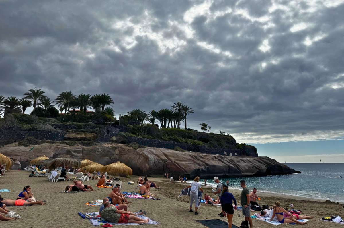 a photo of tourists relaxing on the sand with thatched umbrellas, Playa del Duque, Tenerife, photo by Next Level of Travel
