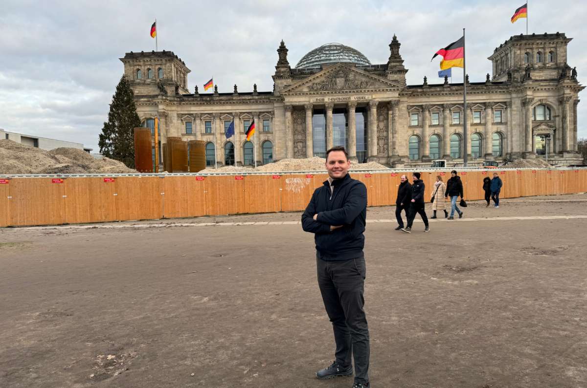 A photo showing a tourist posing in front of the historic Reichstag building in Berlin, Germany, a photo by Next Level of Travel