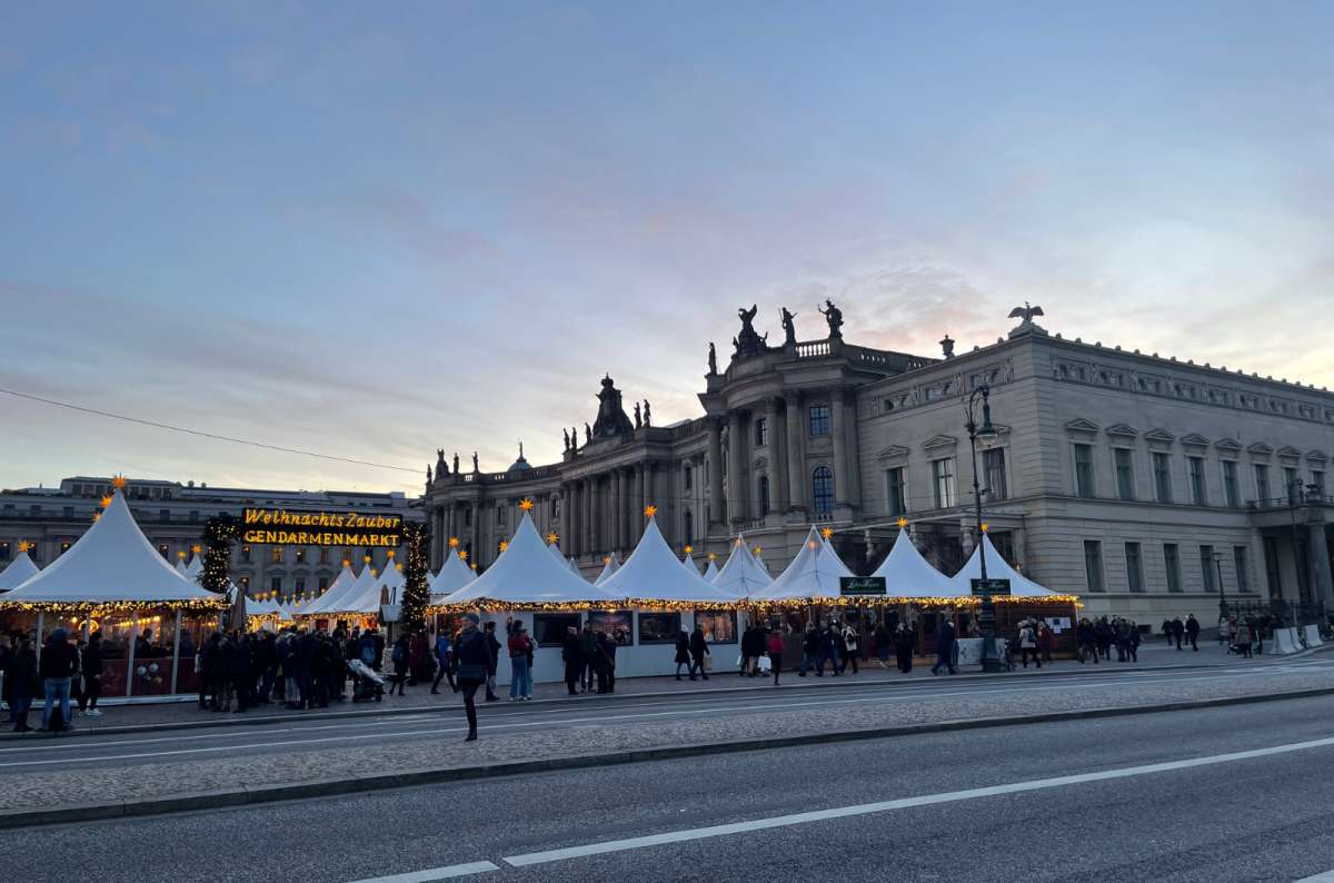 A photo showing the Christmas market in front of the historic Konzerthaus building at Gendarmenmarkt, Germany, a photo by Next Level of Travel