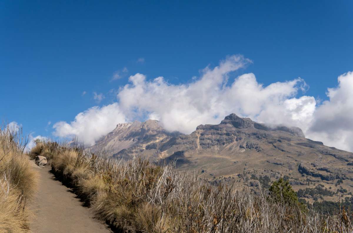 a photo of a dirt trail leading to the cloud-covered peaks of Iztaccíhuatl, Izta Popo National Park, Mexico