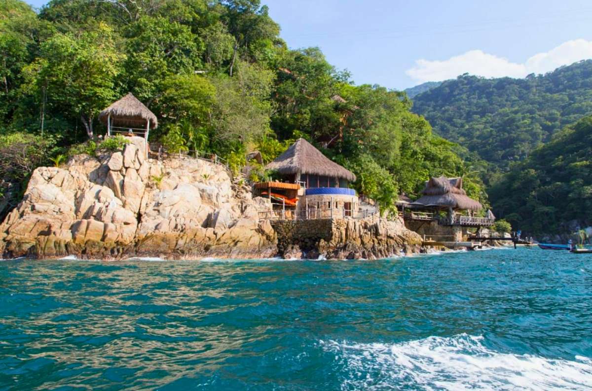 a photo of palapa-roofed houses on the rocky coast near Boca de Tomatlán, Jalisco, Mexico