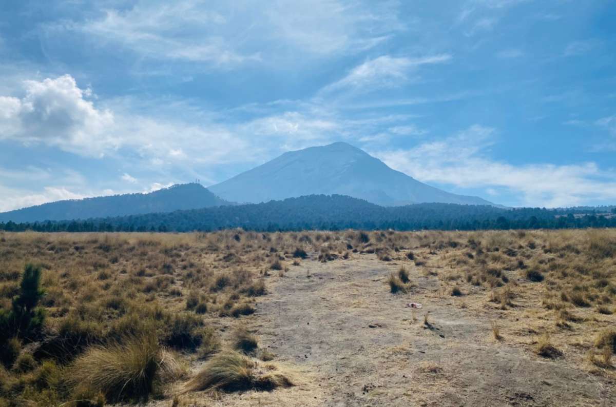 a photo of Popocatépetl rising above a dry grassy plain dotted with bunchgrass, Izta Popo National Park, Mexico, photo by Next Level of Travel