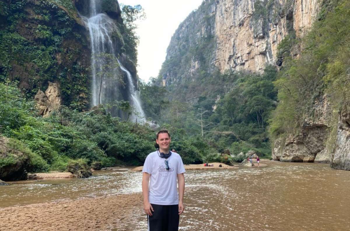 a tourist posing in front of the El Aguacero waterfall and the canyon cliffs in Chiapas, Mexico, photo by Next Level of Travel