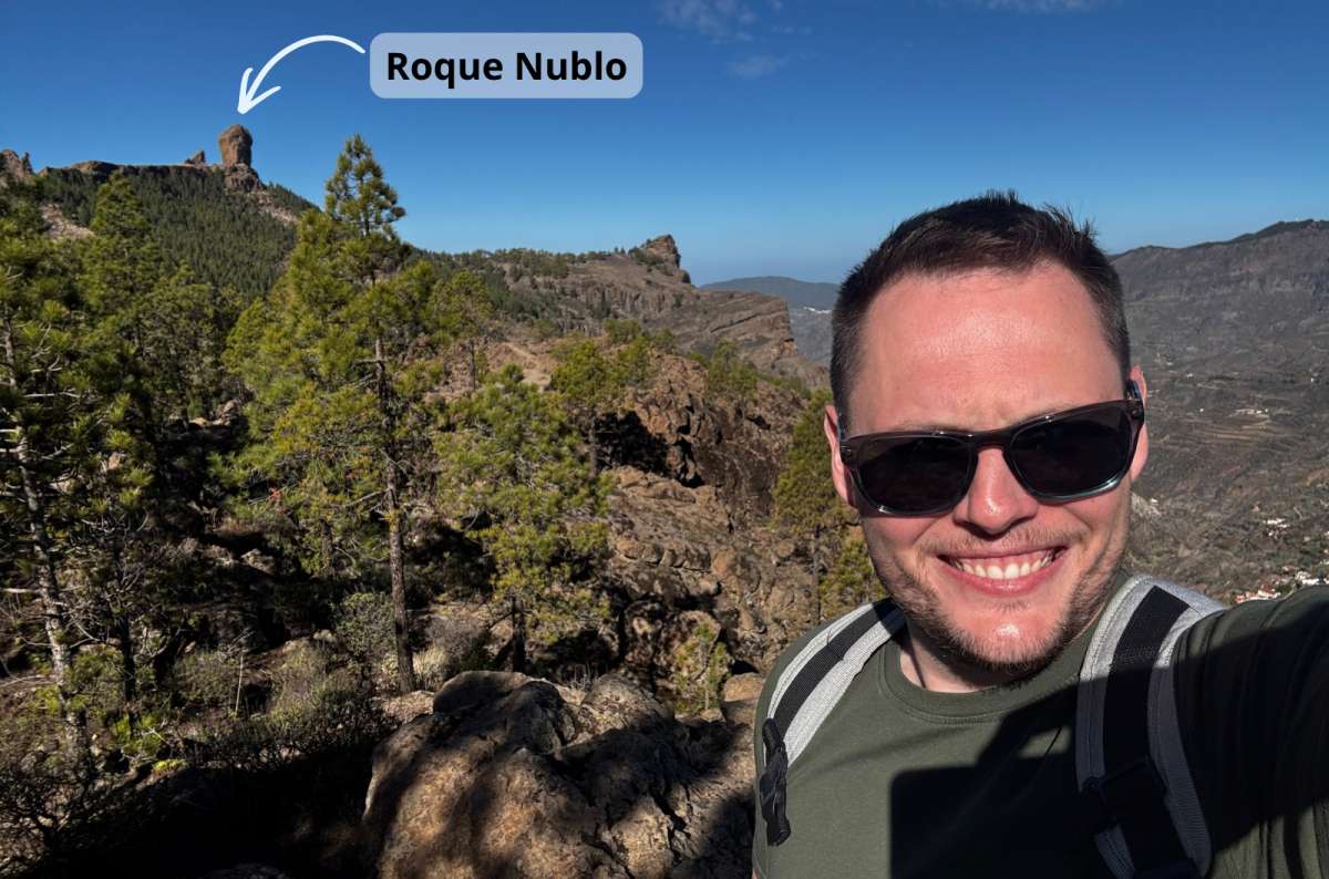 a photo of a tourist taking a selfie on a hike with Roque Nublo highlighted in the background, Canary Islands, photo by Next Level of Travel