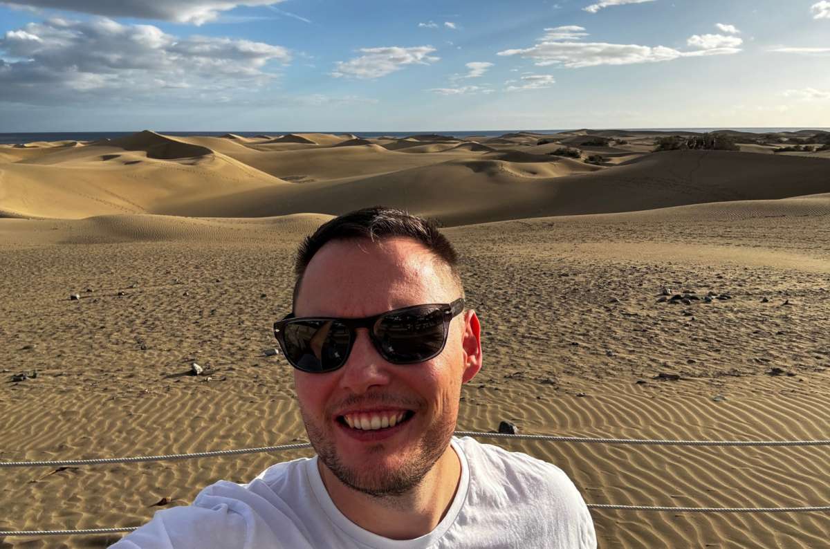 a photo of a tourist taking a selfie with the Maspalomas dunes visible in the background, Canary Islands, photo by Next Level of Travel