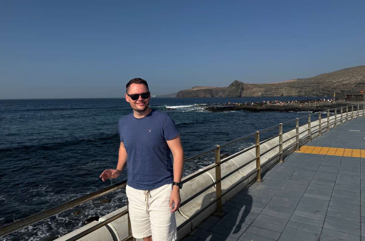 a tourist posing in front of a railing with the sea visible in the background, Agaete, Canary Islands, photo by Next Level of Travel