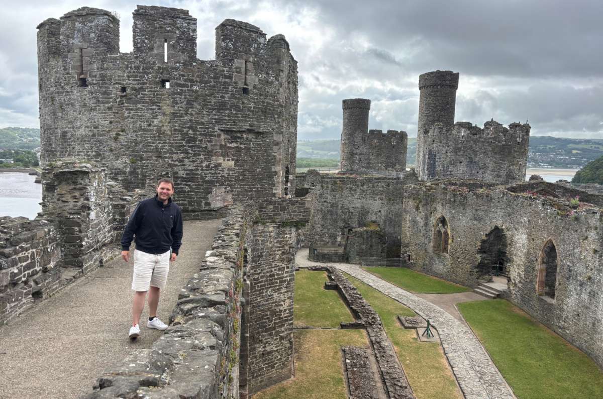 a photo of a tourist on the wall walk of Conwy Castle with its round towers, Conwy, Wales, photo by Next Level of Travel