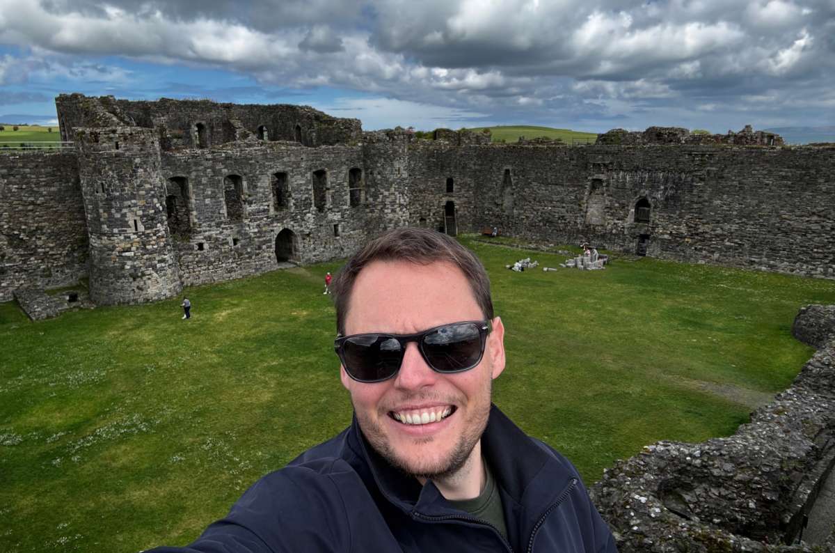 a photo of a tourist taking a selfie above the grassy inner ward of the castle, Beaumaris, Wales, photo by Next Level of Travel