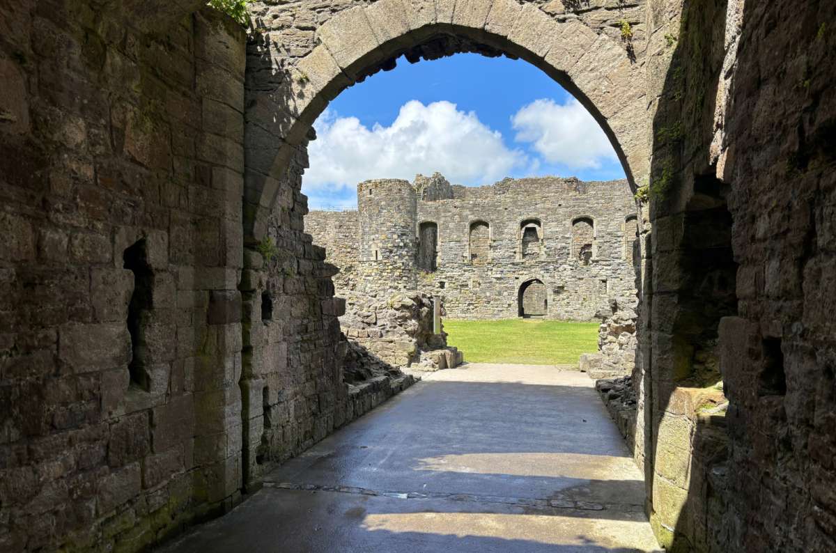 a photo of the inner ward of Beaumaris Castle seen through a stone archway, Beaumaris, Wales, photo by Next Level of Travel