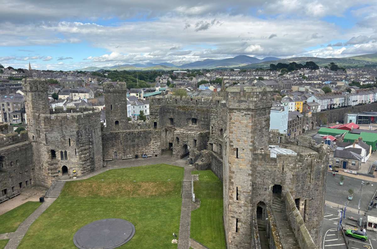 a photo of the inner ward of Caernarfon Castle with the town and mountains behind, Caernarfon, Wales, photo by Next Level of Travel
