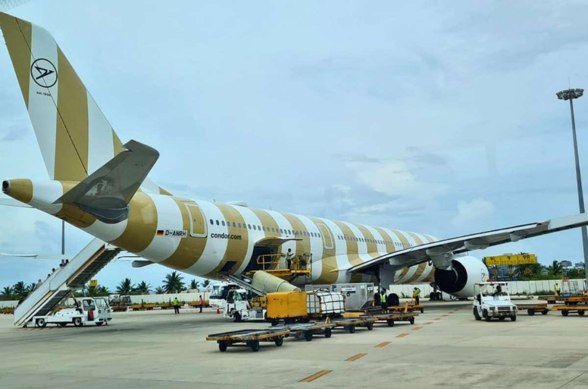 a photo of a Condor Airbus A330neo in gold striped livery at a remote stand with boarding stairs