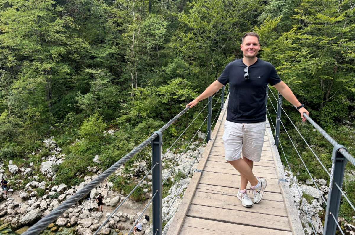 a photo of a tourist on a hanging footbridge above a rocky riverbed, Soča Valley, Slovenia, photo by Next Level of Travel