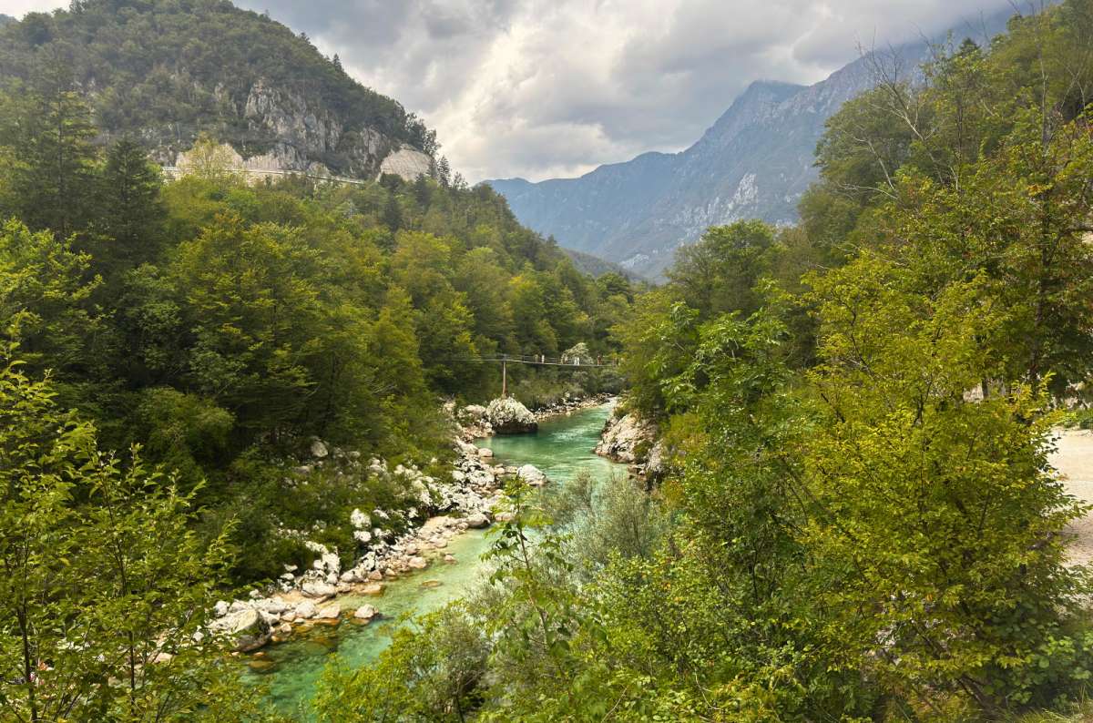 a photo of the Soča River flowing between rocks under a hanging footbridge, Slovenia, photo by Next Level of Travel