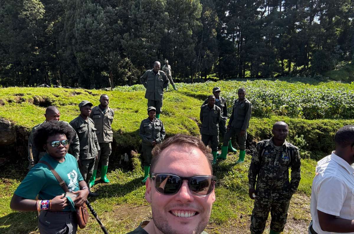 a photo of a tourist with gorilla trekking rangers in Volcanoes National Park, Kinigi, Rwanda, a photo by Next Level of Travel