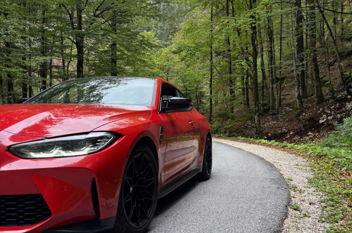 a photo of a red BMW parked on a narrow forest road above Lake Bohinj, Slovenia, photo by Next Level of Travel