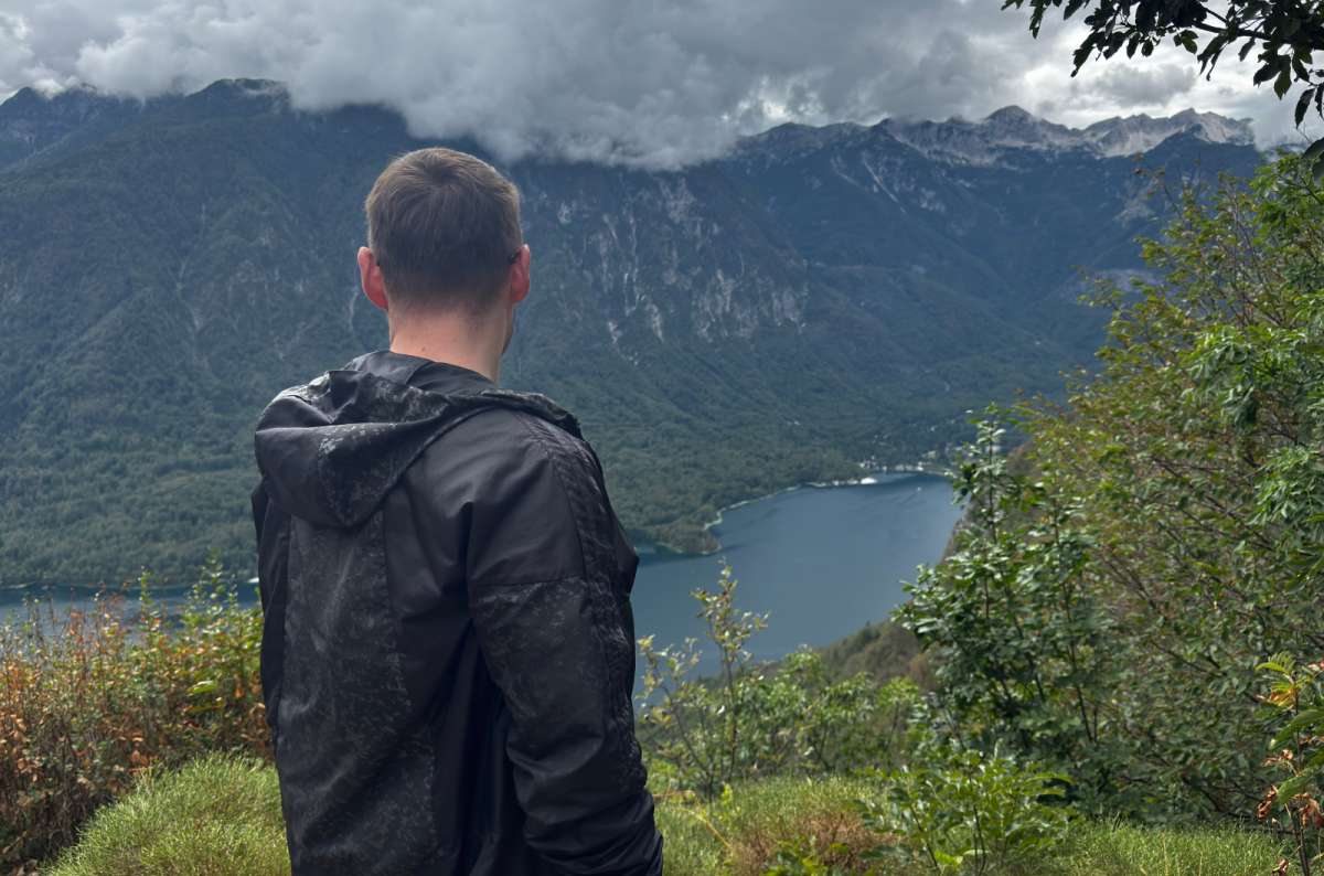 a photo of a tourist in a rain jacket looking down at Lake Bohinj from the Vogar viewpoint, Slovenia, photo by Next Level of Travel