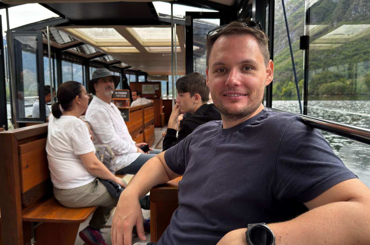 a photo of a tourist sitting on a wooden bench inside the panorama boat on Lake Bohinj, Slovenia, photo by Next Level of Travel