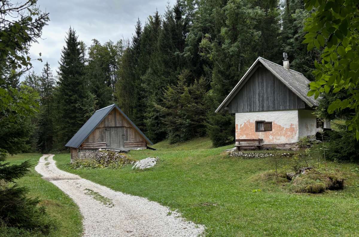 a photo of old wooden herdsmen's huts and a gravel path on a mountain pasture above Bohinj, Planina Vogar, Slovenia, photo by Next Level of Travel
