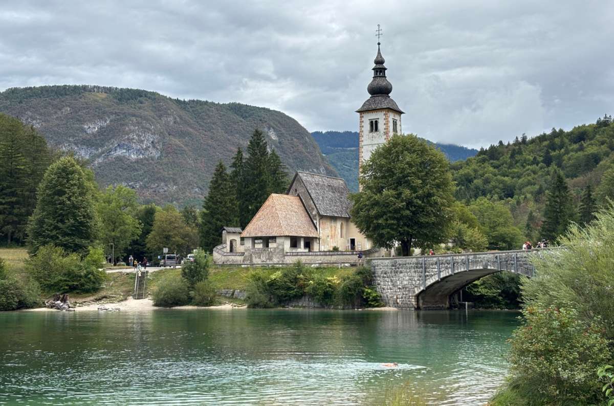 a photo of the Church of St. John the Baptist and the stone bridge on the shore of Lake Bohinj, Ribčev Laz, Slovenia, photo by Next Level of Travel