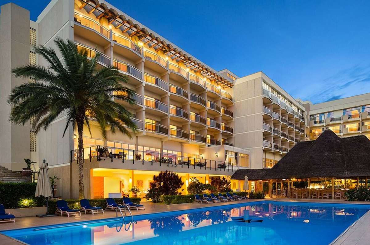 a photo of Hôtel des Mille Collines with its outdoor swimming pool and palm trees in Kigali, Rwanda
