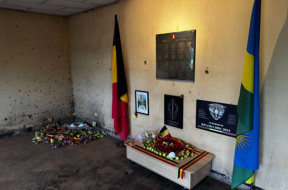 a photo of the memorial room with commemorative plaques, flowers, and Belgian and Rwandan flags at Camp Kigali, Rwanda, a photo by Next Level of Travel