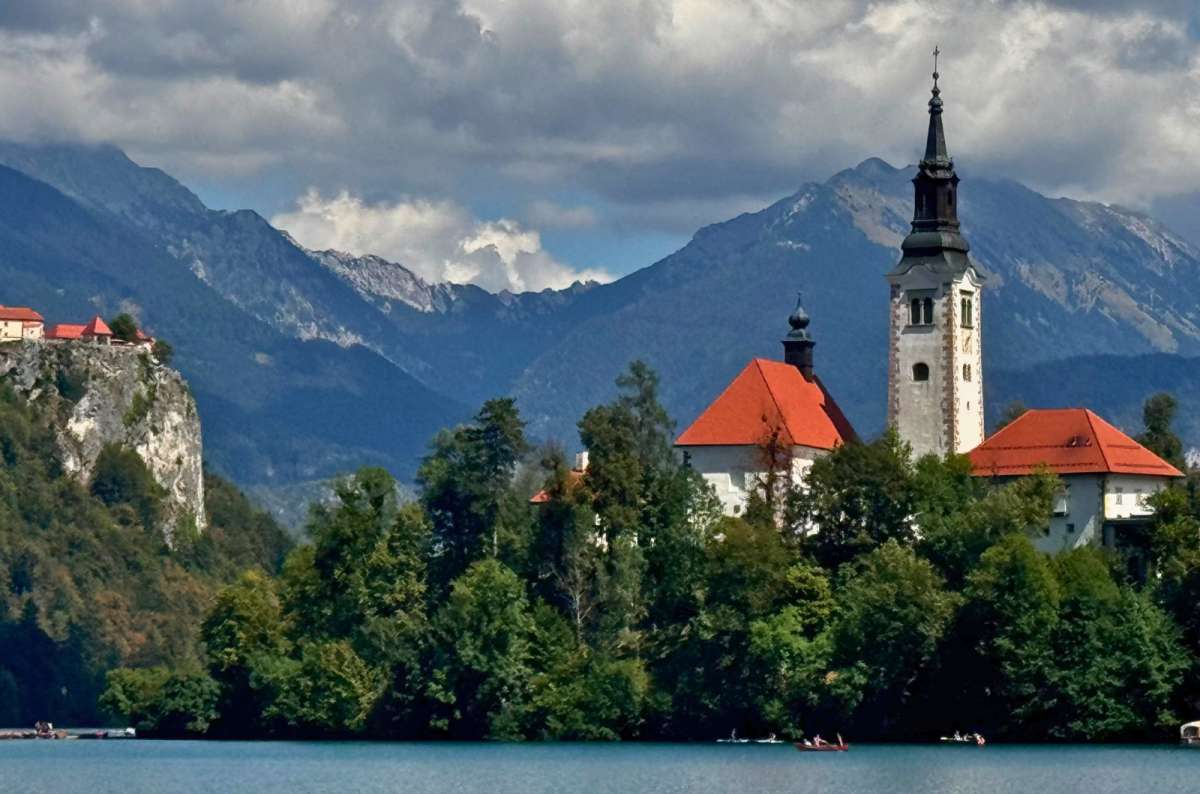 photo of the church on Bled Island with Bled Castle on its cliff and the Julian Alps behind, Lake Bled, Slovenia, photo by Next Level of Travel
