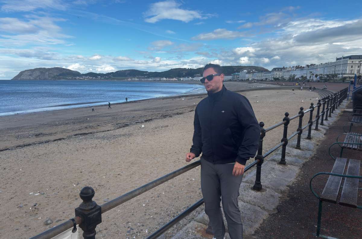 a photo of a tourist on the Llandudno promenade with the beach and the Little Orme behind, Wales, photo by Next Level of Travel