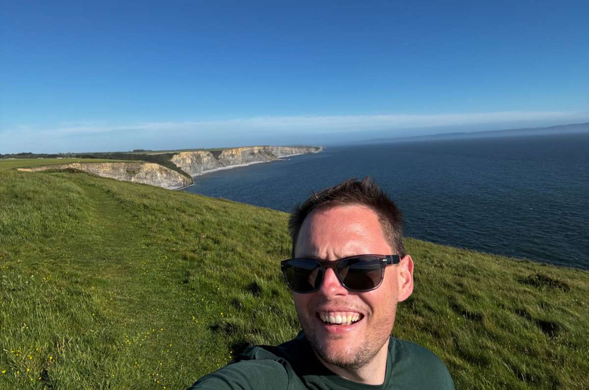a photo of a tourist taking a selfie on the sunny clifftop above Dunraven Bay, Wales, photo by Next Level of Travel
