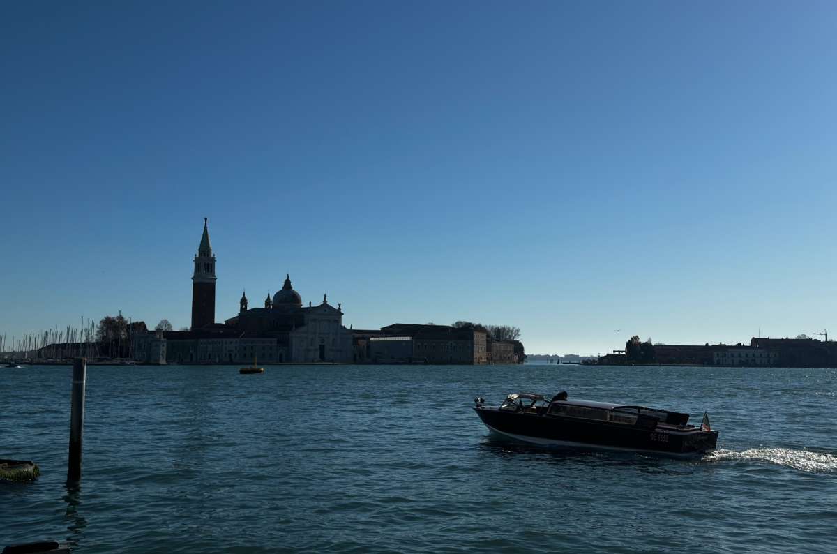 a photo of San Giorgio Maggiore across the lagoon with a water taxi passing in the morning light, Venice, Italy, photo by Next Level of Travel