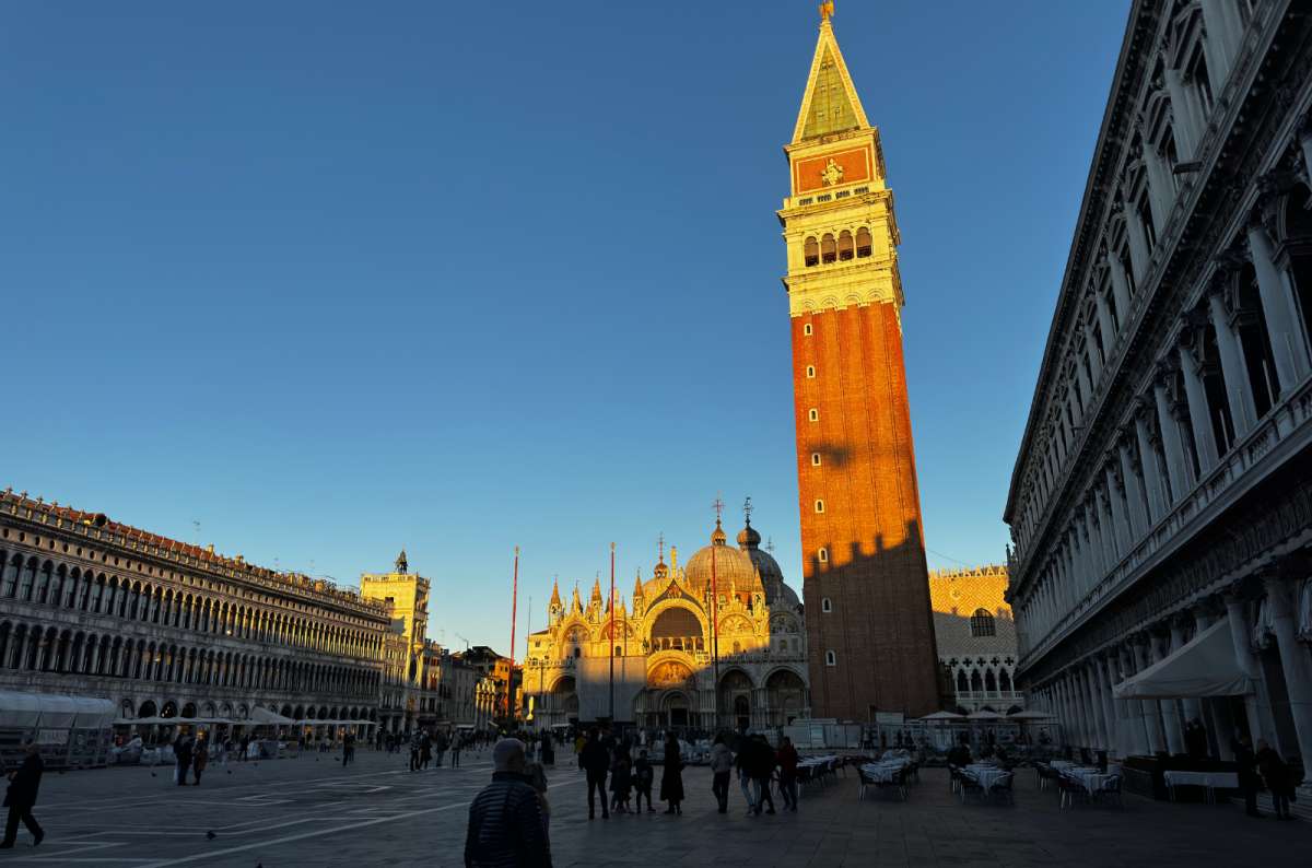 a photo of St. Mark's Square with the Campanile glowing orange in the late sun and the basilica behind, Venice, Italy, photo by Next Level of Travel