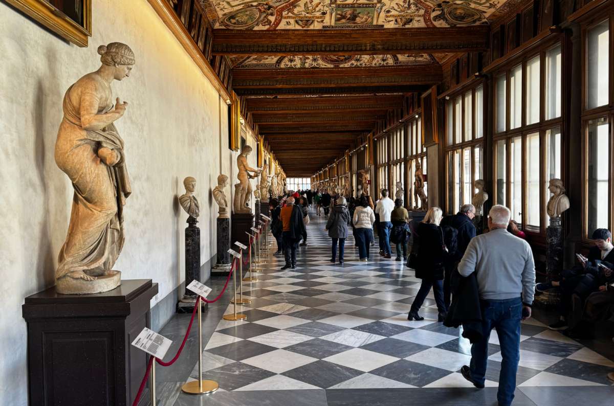a photo of the long Uffizi corridor with a checkered floor, painted ceiling and classical statues, Florence, Italy, photo by Next Level of Travel