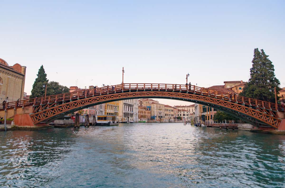 a photo of the wooden Accademia Bridge arching over the Grand Canal in the evening light, Venice, Italy