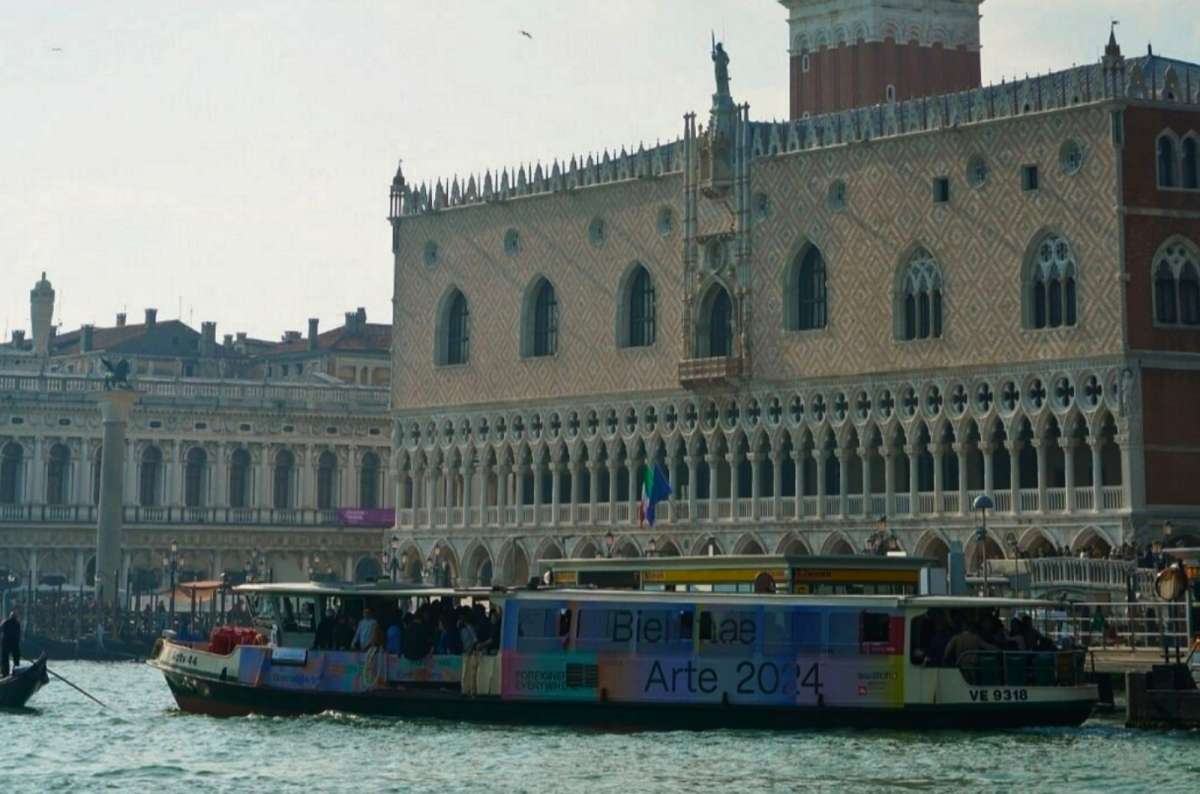 a photo of a crowded vaporetto water bus passing Doge’s Palace on the San Marco waterfront, Venice, Italy