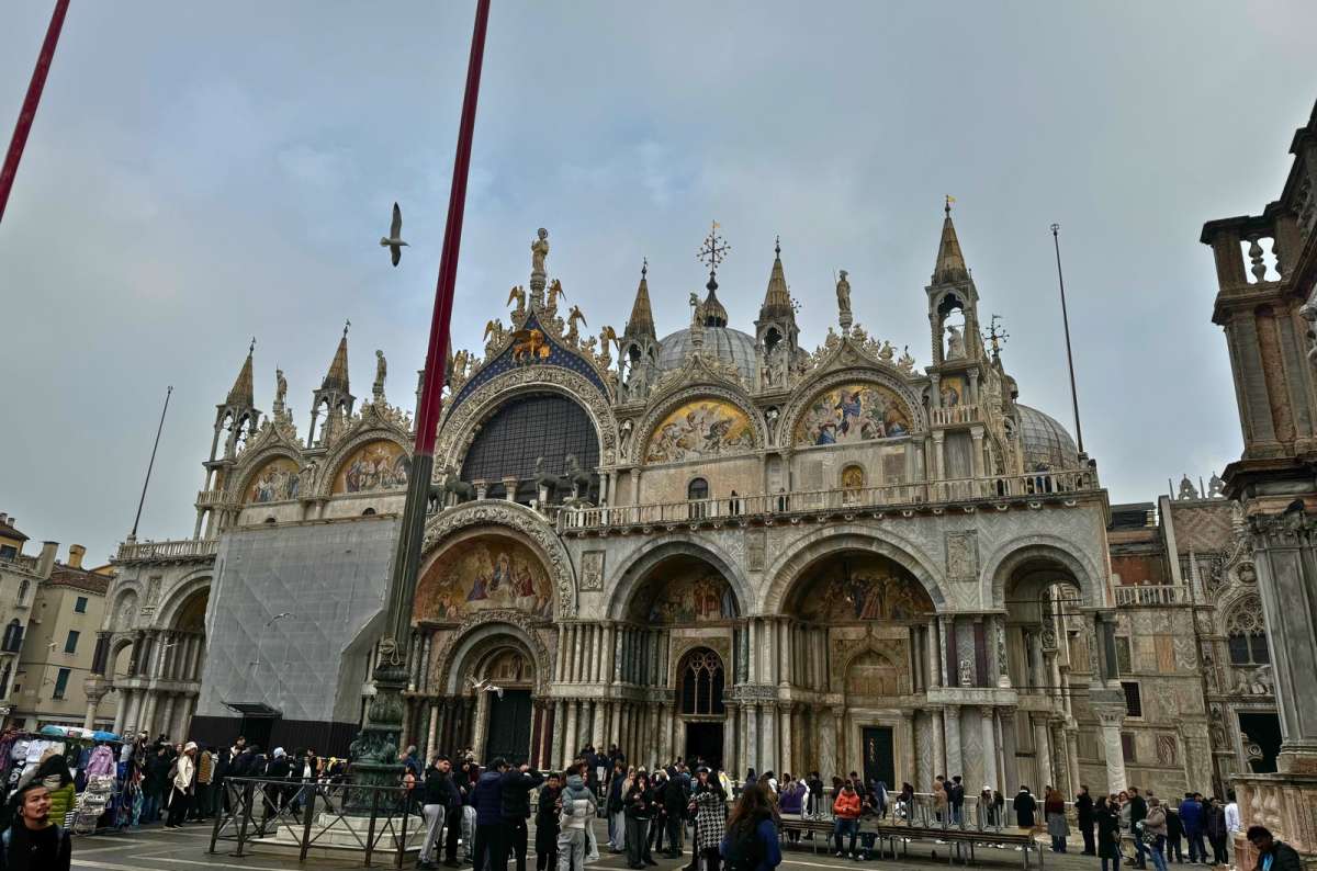 a photo of the facade of St. Mark’s Basilica with crowds of tourists outside the entrance on Piazza San Marco, Venice, Italy, photo by Next Level of Travel