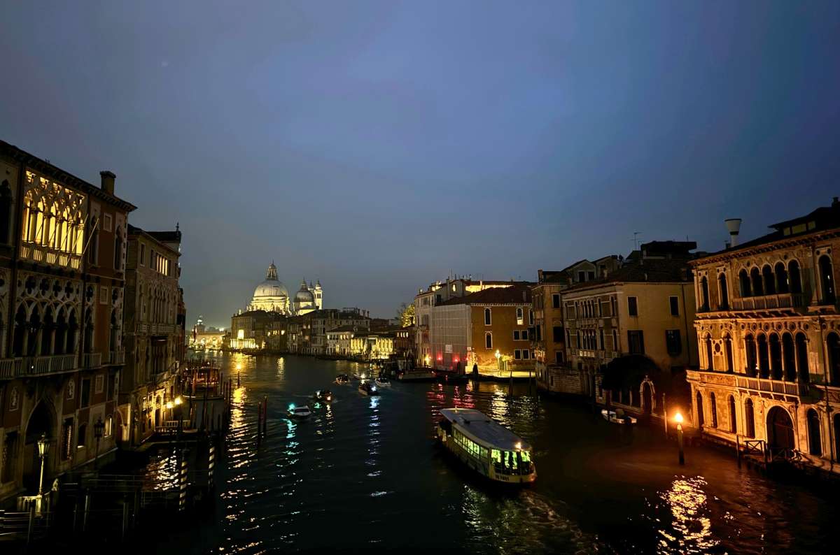 a photo of the Grand Canal at night with Santa Maria della Salute lit up and a vaporetto seen from Ponte dell’Accademia, Venice, Italy, photo by Next Level of Travel