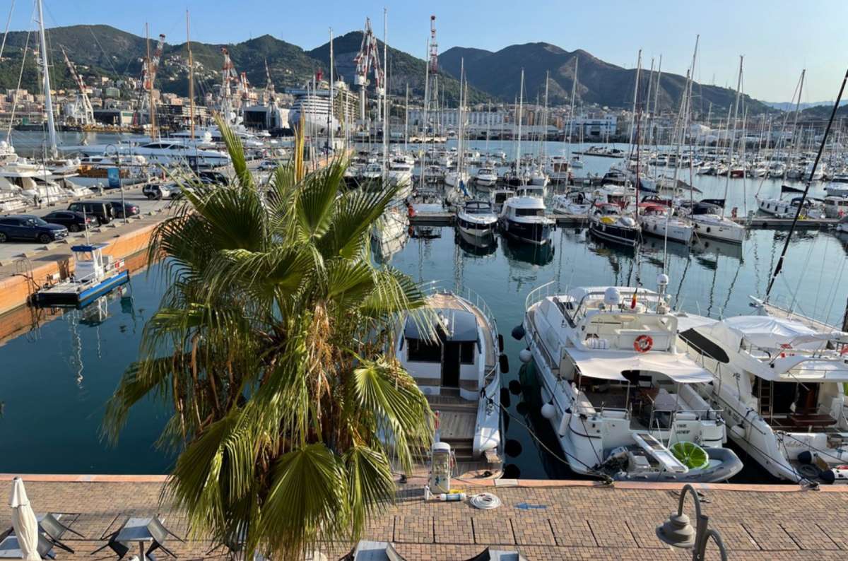 a photo of a marina full of yachts with the hills of the city rising behind, Genoa, Italy, photo by Next Level of Travel