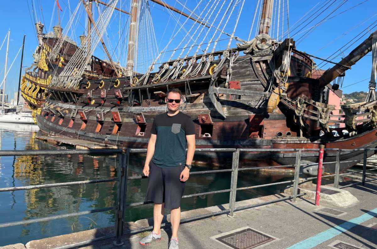 a photo of a tourist standing in front of the Neptune replica galleon moored at Porto Antico, Genoa, Italy, photo by Next Level of Travel