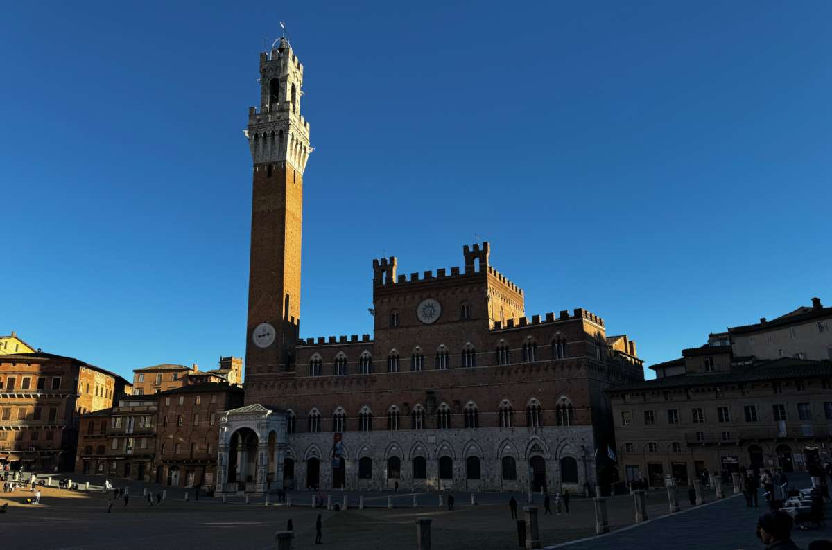 a photo of Piazza del Campo with Palazzo Pubblico and Torre del Mangia under a deep blue sky, Siena, Tuscany, Italy, photo by Next Level of Travel