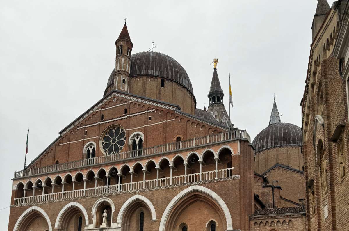 a photo of the brick facade and domes of the Basilica of Saint Anthony under a cloudy sky, Padua, Italy, photo by Next Level of Travel