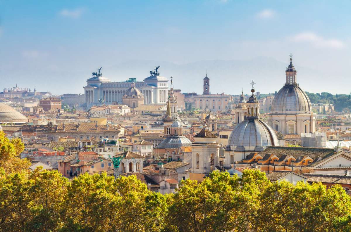 a photo of the rooftops and church domes of Rome with the Vittoriano monument on the skyline, Rome, Italy