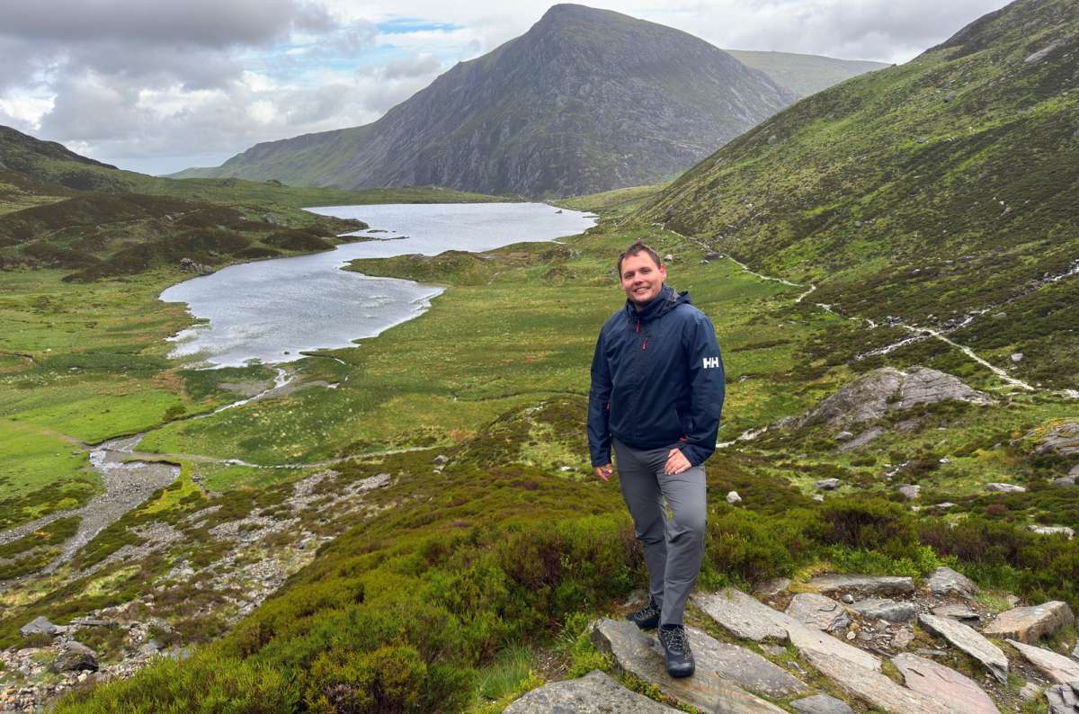 a photo of a tourist in a rain jacket on the path above Llyn Idwal in Cwm Idwal, Snowdonia, Wales, UK, photo by Next Level of Travel