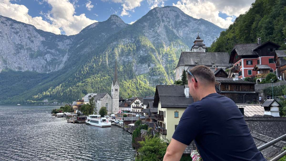 a photo of a tourist looking at Hallstatt village and Hallstätter See below the Dachstein mountains, Austria, photo by Next Level of Travel