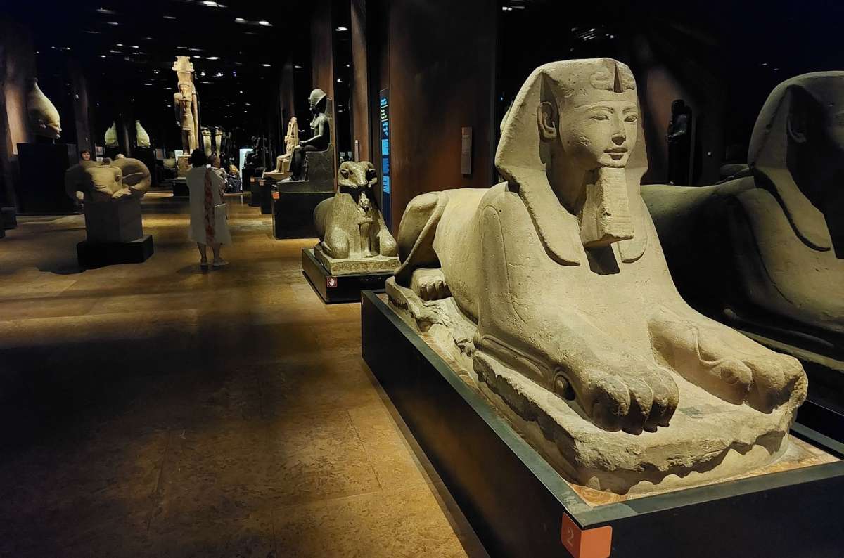 a photo of a row of ancient sphinxes in a dimly lit gallery of the Egyptian Museum, Turin, Italy, photo by Next Level of Travel