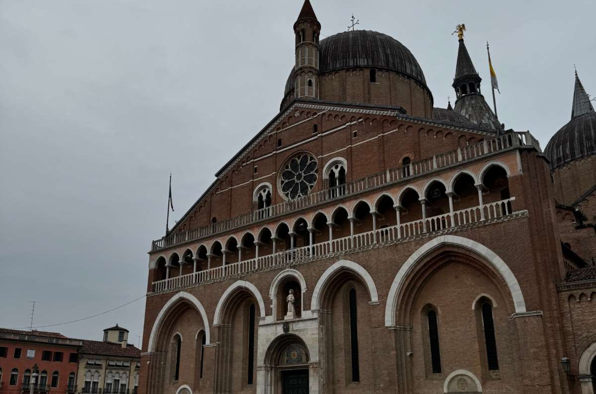 a photo of the Basilica of Saint Anthony with its domes and bell towers under a cloudy sky, Padua, Italy, photo by Next Level of Travel