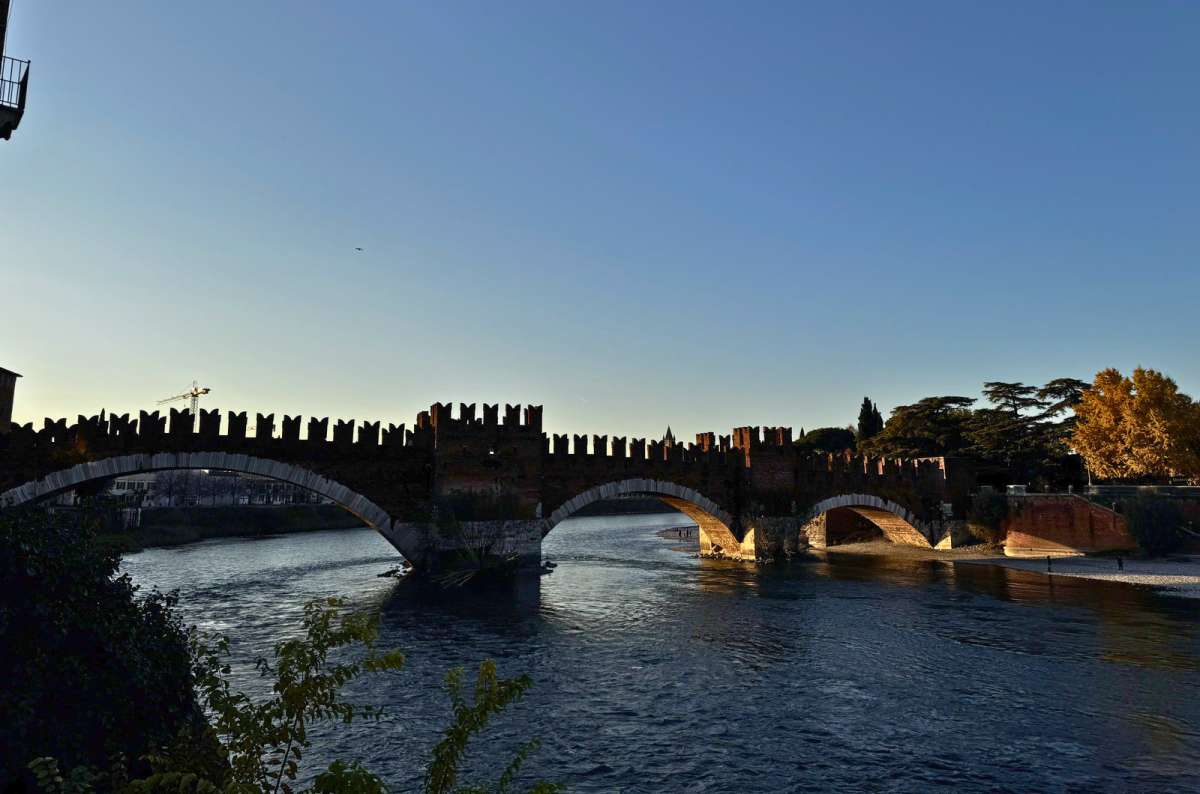 a photo of the battlements of Ponte Scaligero over the Adige River at dusk seen from the opposite bank, Verona, Italy, photo by Next Level of Travel